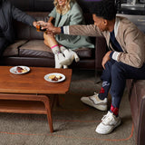 Three people sitting on a couch with a coffee table in front of them, enjoying snacks and drinks.