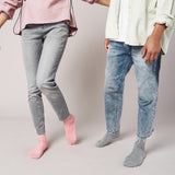 Two people wearing jeans and socks on a plain background thumbnail