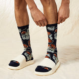 Person wearing navy socks with fox pattern and white sandals on a light background thumbnail