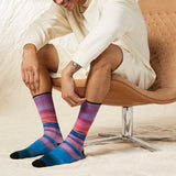 Person wearing colorful striped socks sitting on a chair. thumbnail