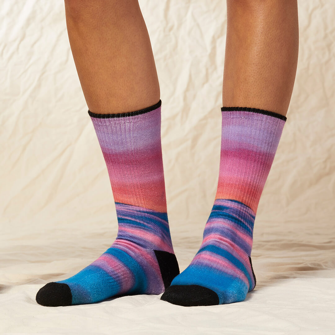 Multicolored striped socks worn by a person on a neutral background