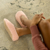 Person wearing pink fuzzy slippers on a textured surface