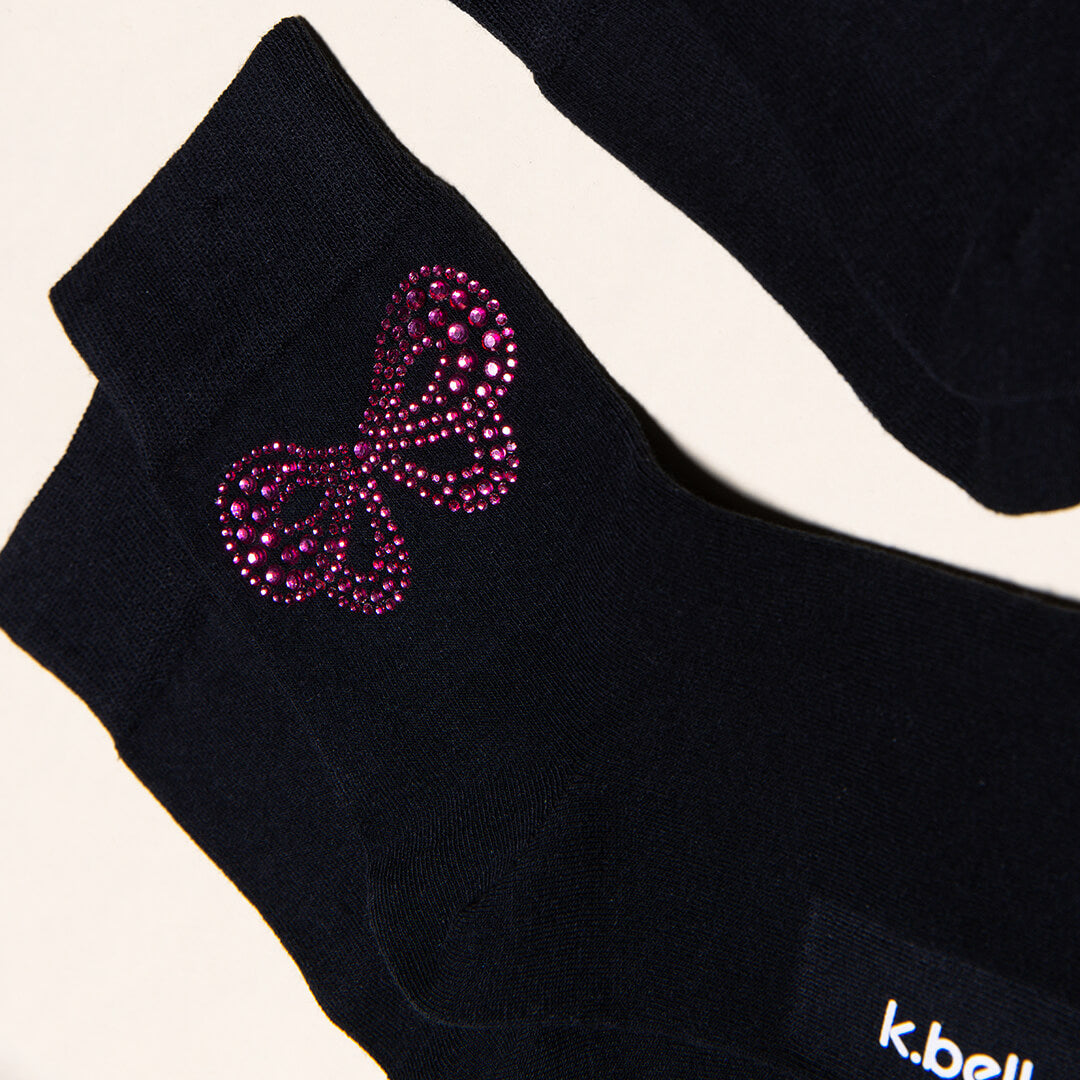 Black socks with a rhinestone bow design and 'k.bell' branding.