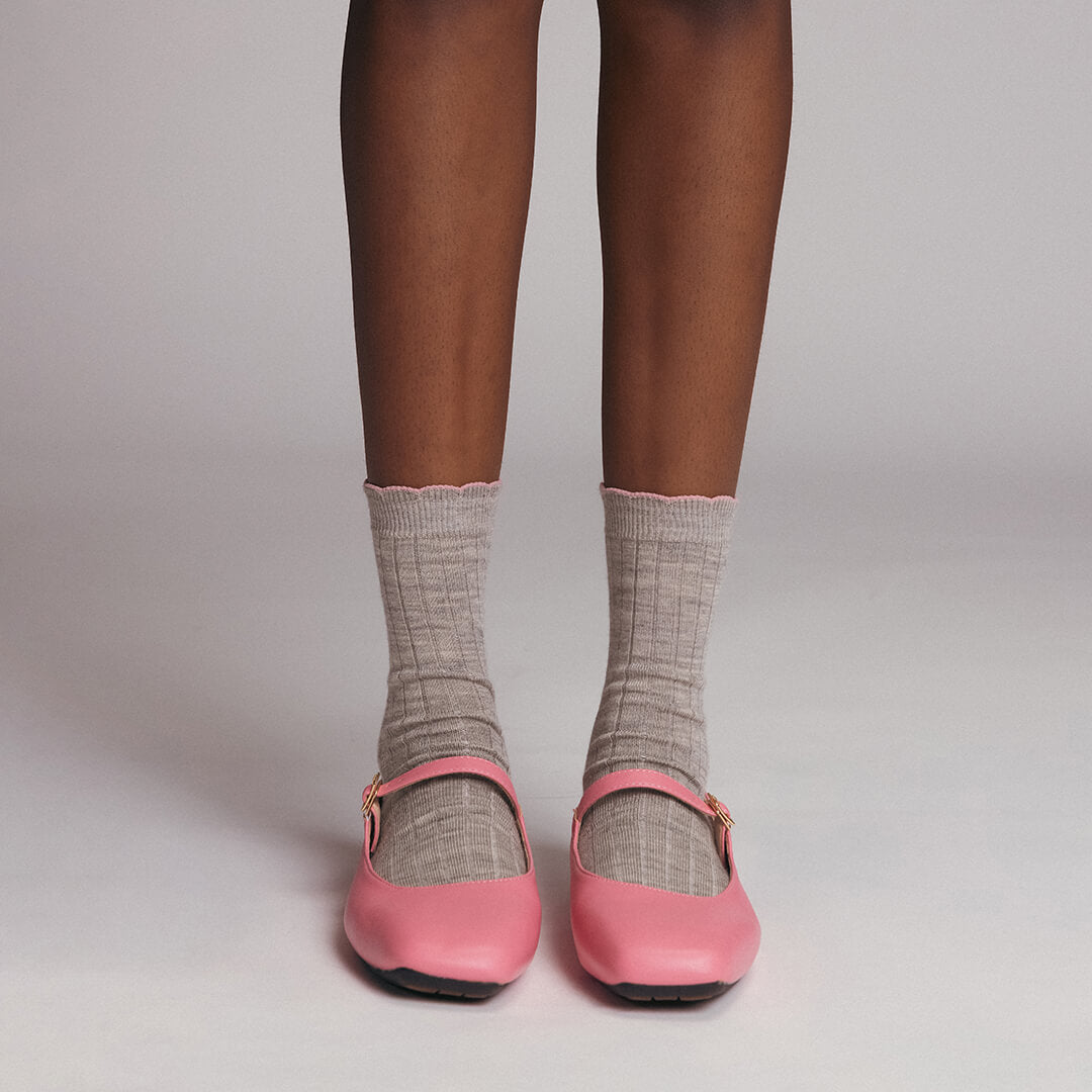Pink shoes worn with gray socks on a neutral background
