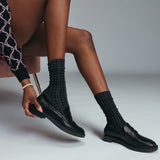 Person wearing black dress shoes and pointelle socks on a neutral background thumbnail