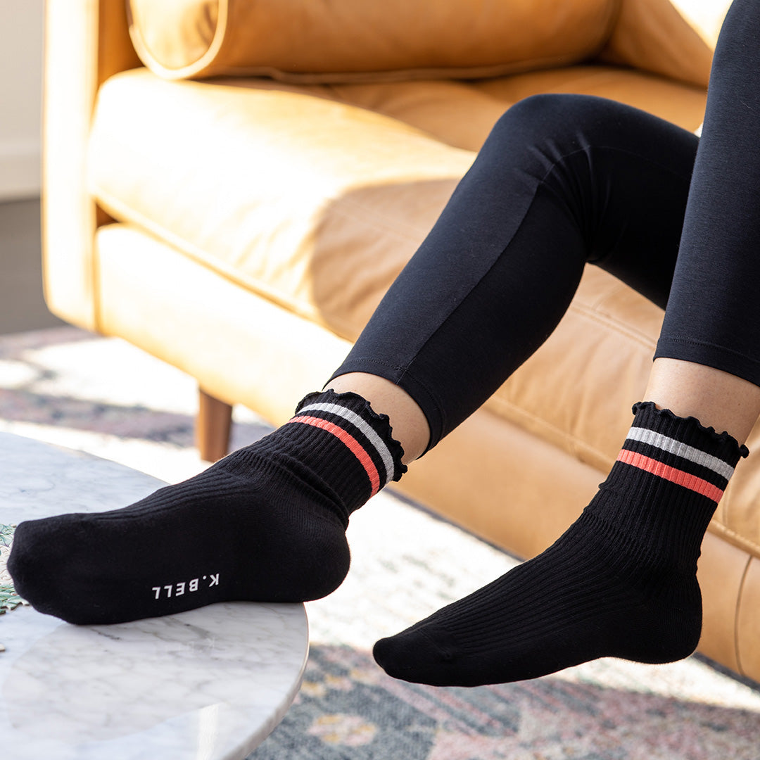 Person wearing black socks with striped cuffs in a living room setting