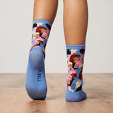 Blue socks with colorful patterns worn by a person on a wooden floor.