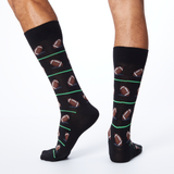 Back view of HOTSOX men's black crew socks on model with a repeat football pattern. thumbnail